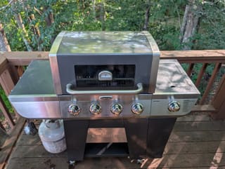 Stainless steel Cuisinart four-burner propane grill with side burner on the lower deck