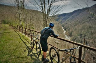 Mountain bikers pausing beside the Blackwater Canyon Trail overlooking a forested mountainside