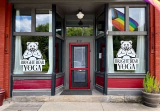 Bright Bear Yoga storefront with bear logos in the windows and the entrance at 212 East Avenue