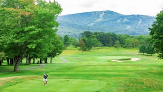 Golfer teeing off on the Canaan Valley Resort course below the mountains