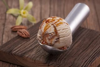 Scoop of caramel-drizzled ice cream on a wooden table