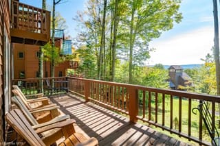 Lower deck with Adirondack chairs and view towards mountains in summer