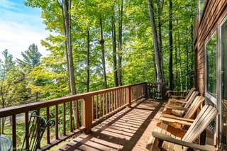 Lower deck with Adirondack chairs and view towards mountains in summer