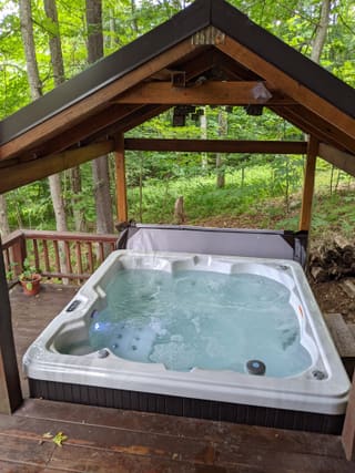 Running hot tub beneath a timber roof on the wooded lower deck